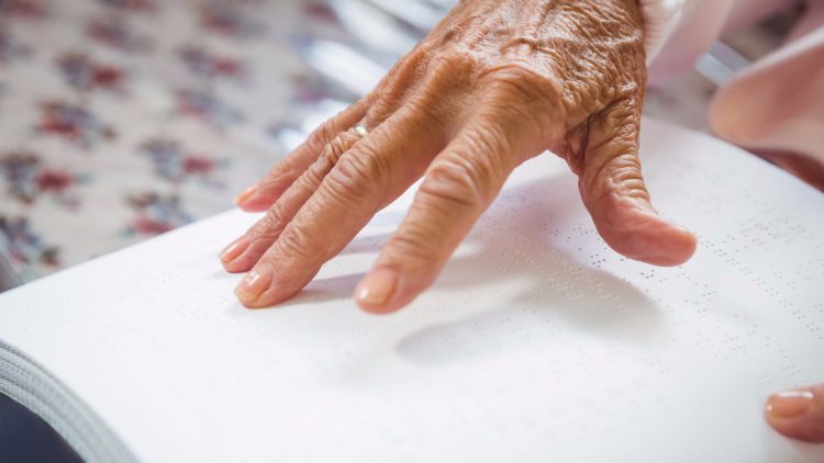Mit den Händen lesen - Ältere Frau liest ein in Blindenschrift verfasstes Buch