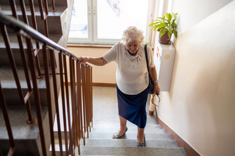 Seniorin geht die Treppen hinauf