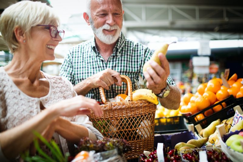 Älteres Ehepaar kauft auf dem Markt Obst ein