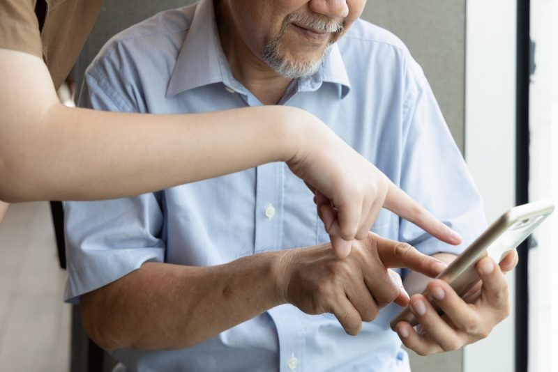 Teenager zeigt älterem Mann etwas auf dem Smartphone
