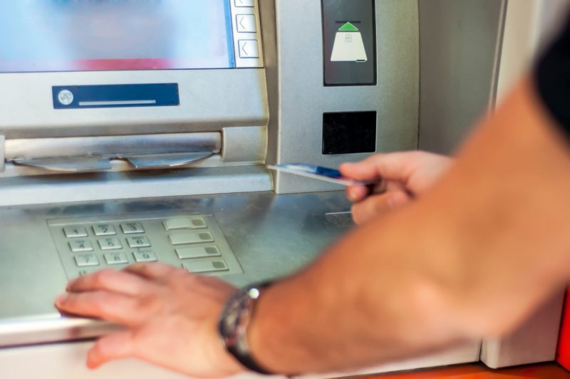 Männliche Person erledigt Bankgeschäfte am Automaten