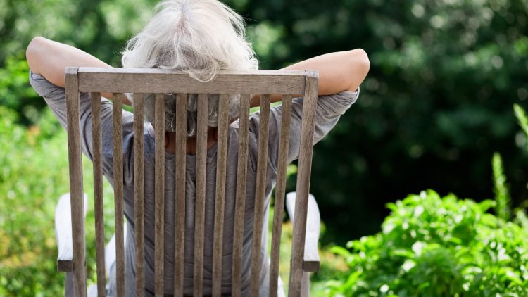 Seniorin sitzt entspannt im Gartenstuhl