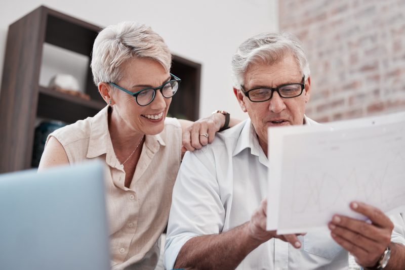 Zufriedenes älteres Ehepaar geht Dokument über Finanzen durch