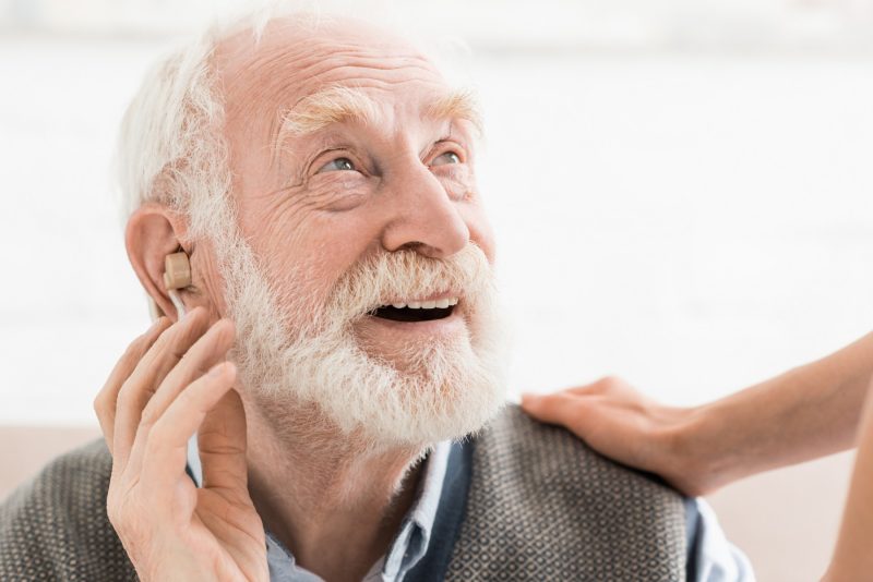 Glücklicher Senior trägt Hörgerät