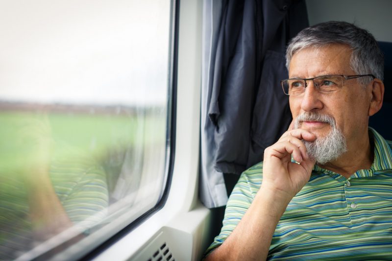 Älterer Mann sitzt im Zug