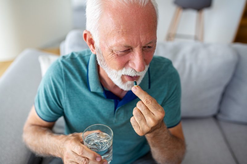 Älterer Mann nimmt Medikament ein