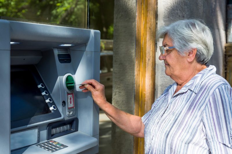 Seniorin nutzt Geldautomat