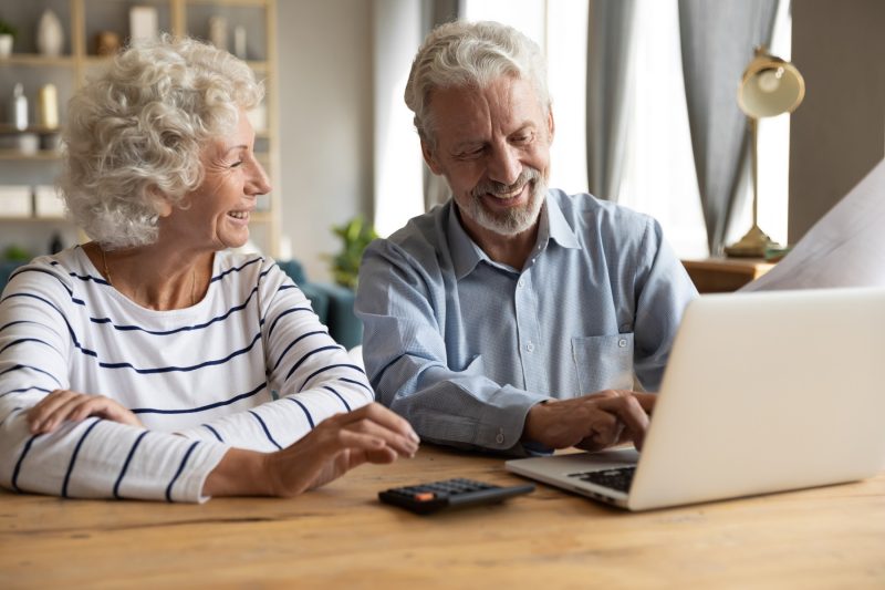 Lächelndes älteres Ehepaar arbeitet am Laptop