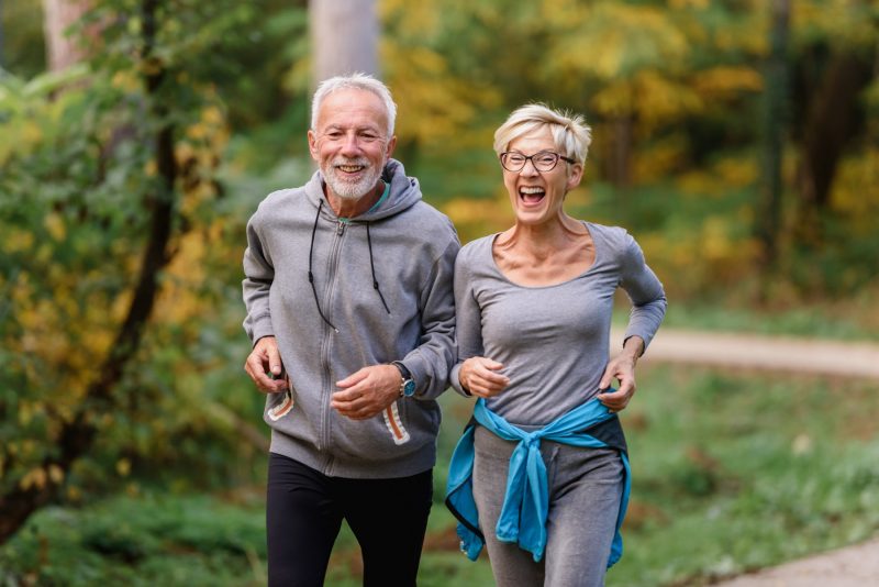 Älteres Paar joggt durch Wald
