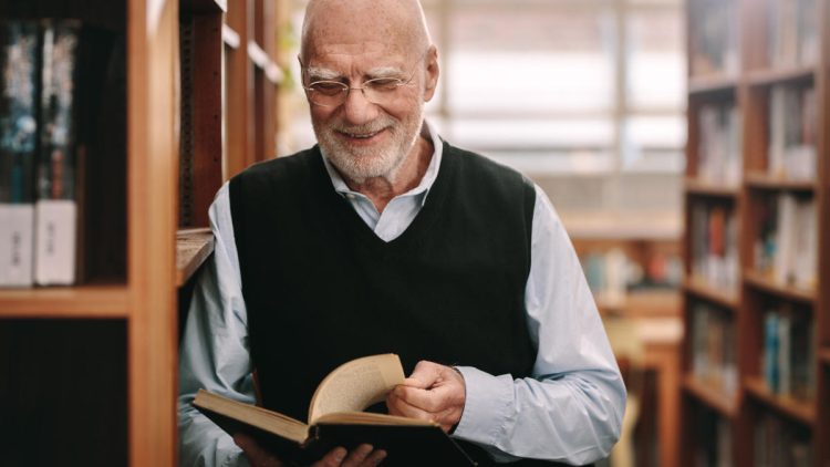 Älterer Mann lächelnd bei Durchblättern eines Buches