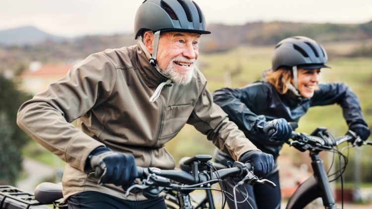 Fröhlicher älterer Herr in Raserhaltung auf dem Fahrrad