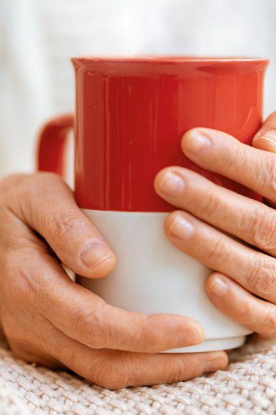 Die richtige Ernährung bei Erkältung oder Grippe - Hände an wärmender Tasse