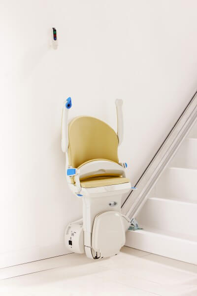 SANIMED 10 plus Sitzlift für gerade Treppen in Startposition in einem weißen Treppenhaus