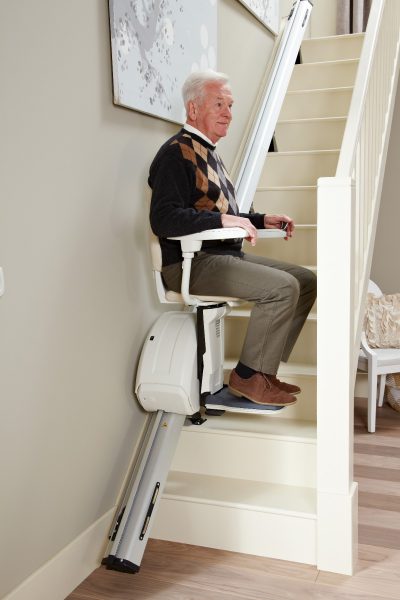 Premium Treppenlift für gerade Treppen Mann fährt die Treppe hinauf